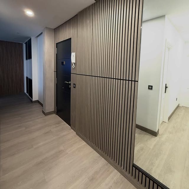 Hall de vivienda con pavimento y revestimiento de lamas, obra de CRIGARMO CANARIAS.